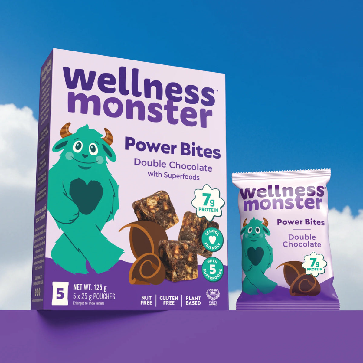 Wellness Monster Double Chocolate Power Bites box and individual pouch on a purple platform against blue sky background